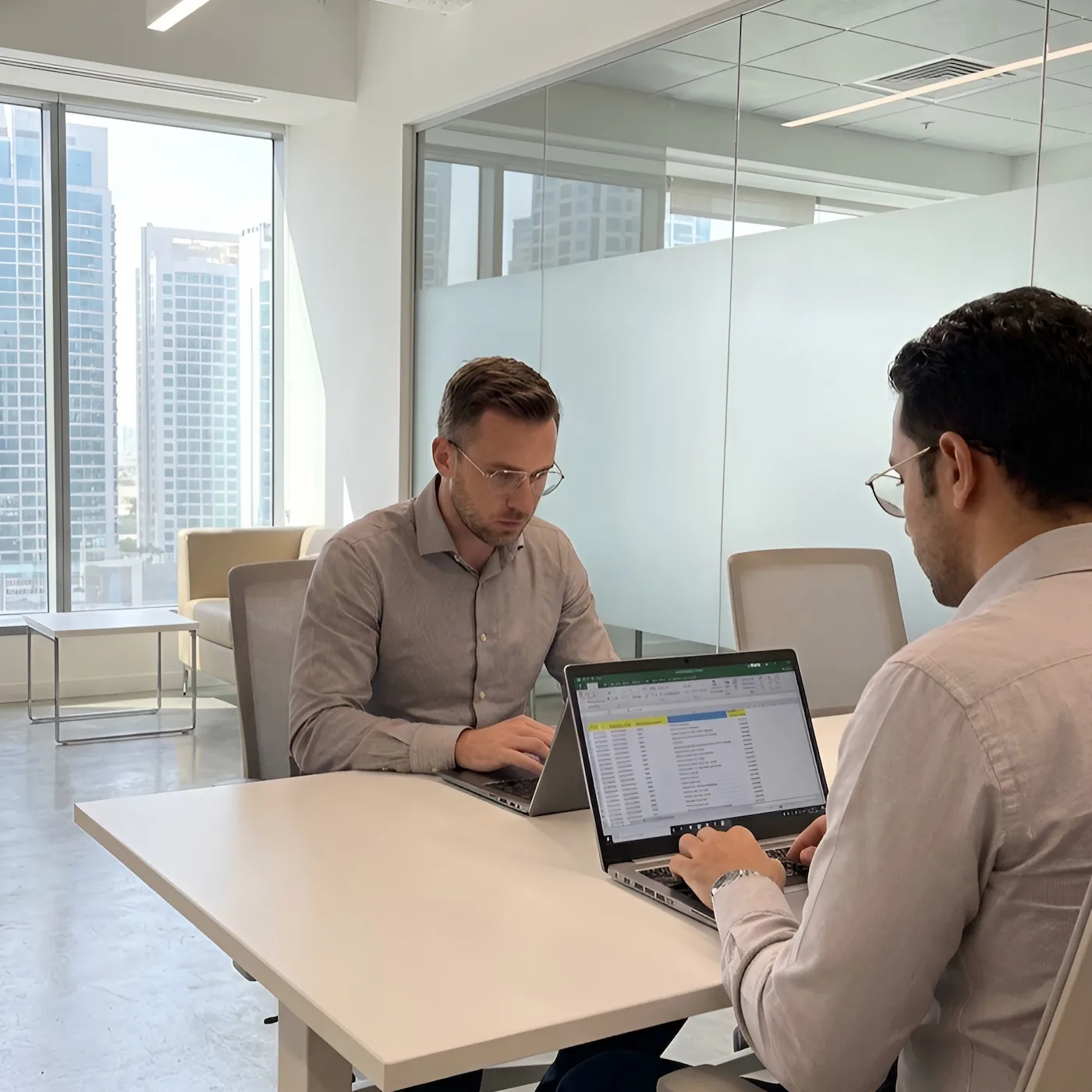 Two professionals actively working together on accounting information in a real UAE office environment